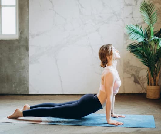 Mujer estirando la espalda sobre una esterilla azul