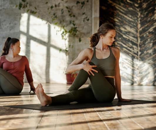 Varias mujeres sentadas en esterillas haciendo pilates